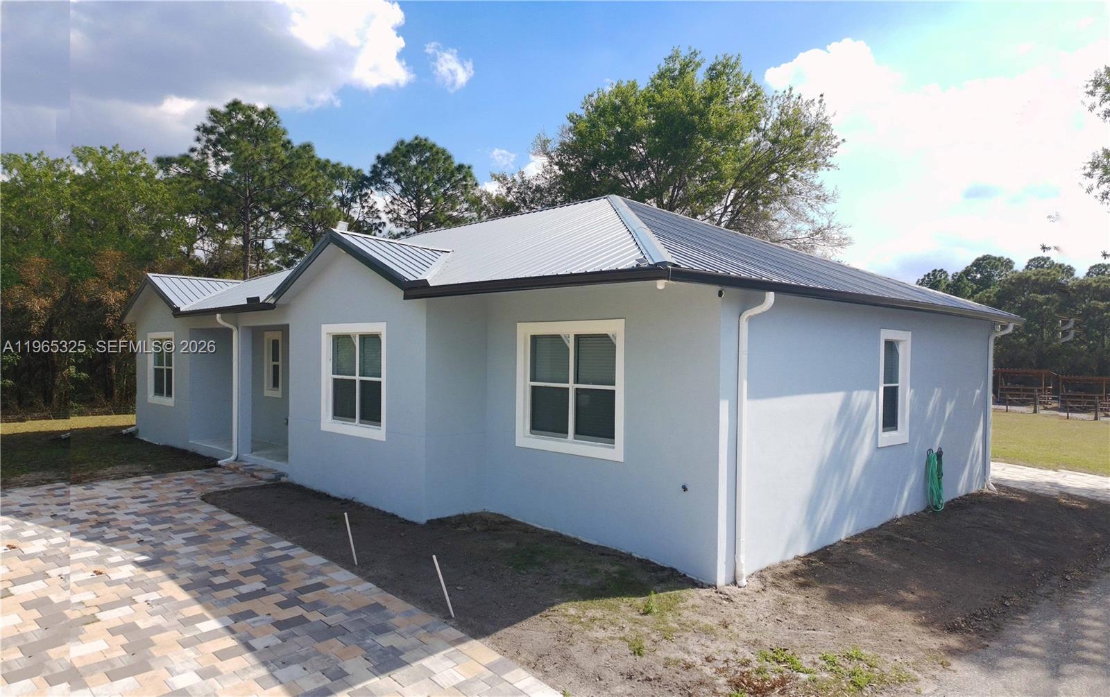 A light blue, single-story house with a metal roof and a paved walkway — 548 Bald Cypress Ave, Clewiston FL 33440, CLEWISTON, FL