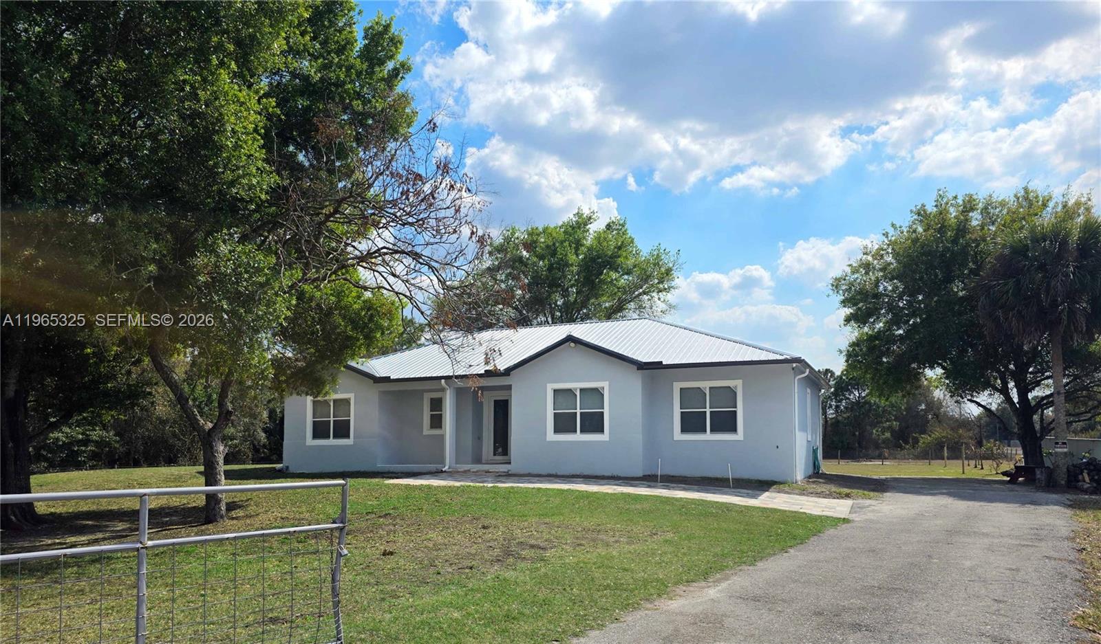 A light gray single-story house with a metal roof sits on a grassy lot — 548 Bald Cypress Ave, Clewiston FL 33440, CLEWISTON, FL