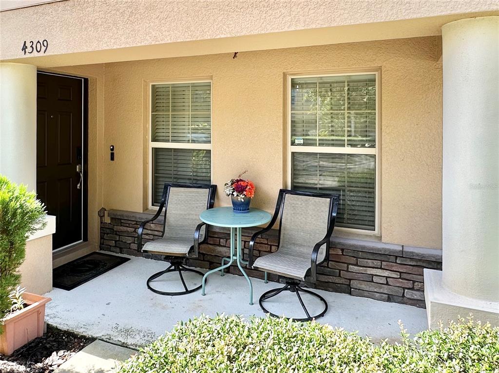 A covered front porch features two chairs, a small table, and stone veneer accents — 4309 REGAL TOWN LANE, LAKE MARY, FL
