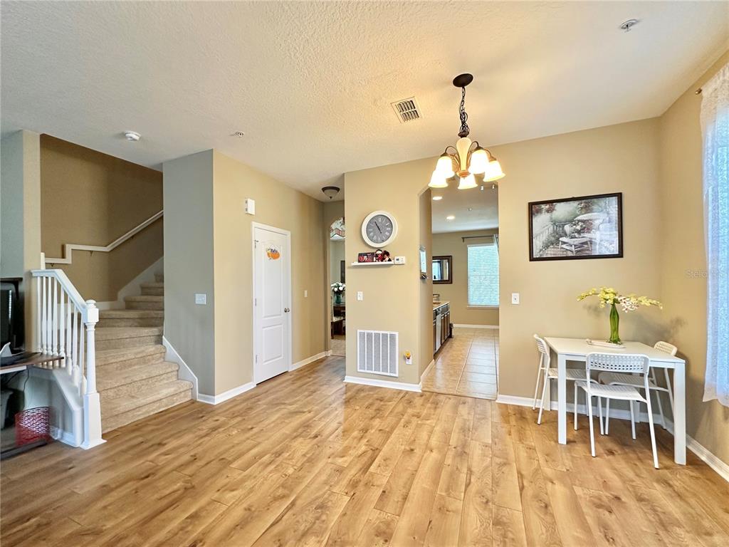 A dining area with wood-look flooring, a staircase, and an adjacent kitchen view — 4309 REGAL TOWN LANE, LAKE MARY, FL