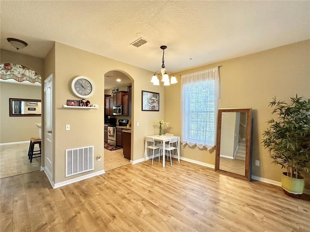 A dining area with wood-look flooring, a small table, a large floor mirror, and an arched entryway — 4309 REGAL TOWN LANE, LAKE MARY, FL