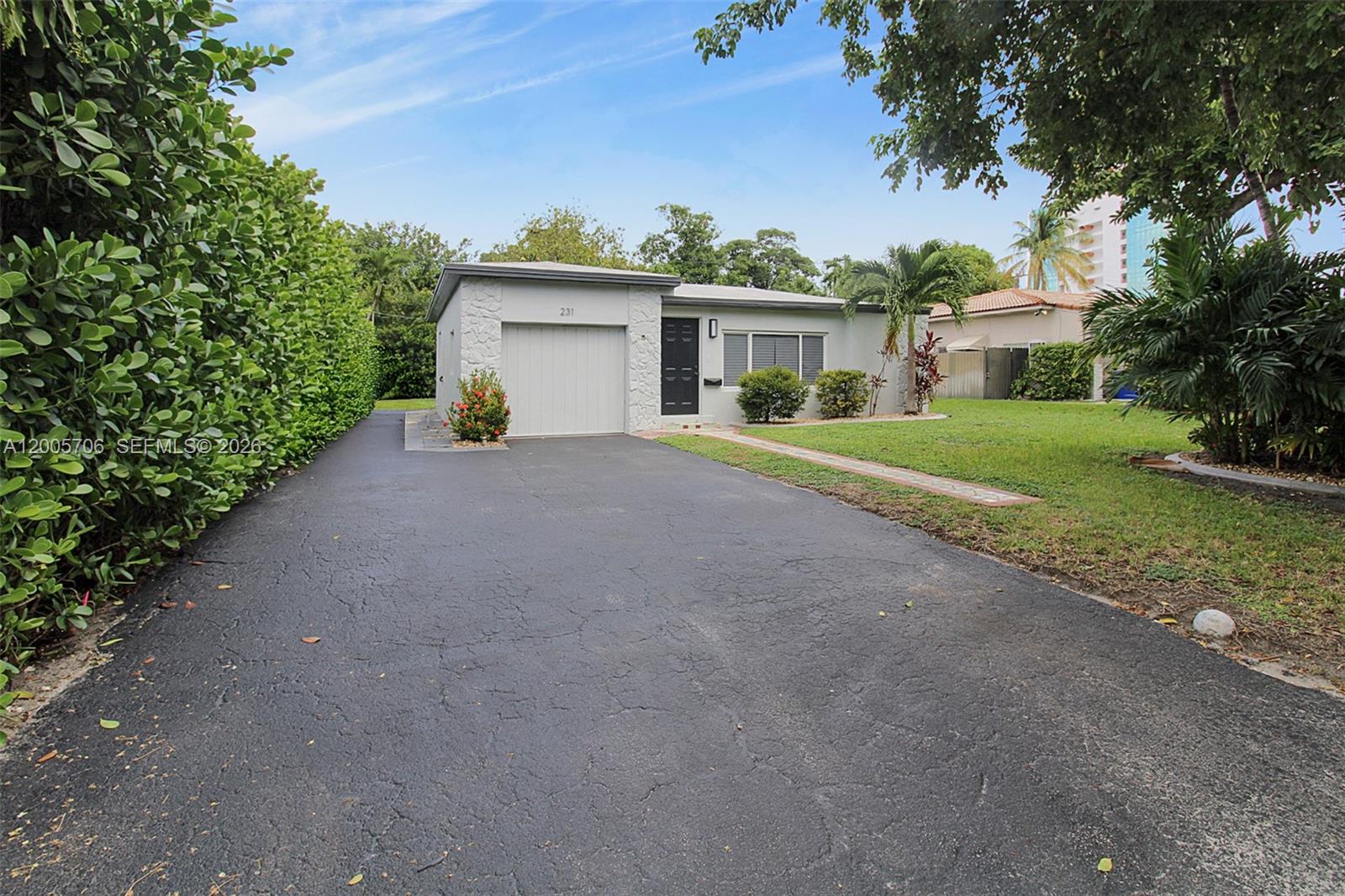 A single-story house with a garage, a paved driveway, and a large hedge — 231 NE 43rd St, Miami FL 33137, MIAMI, FL