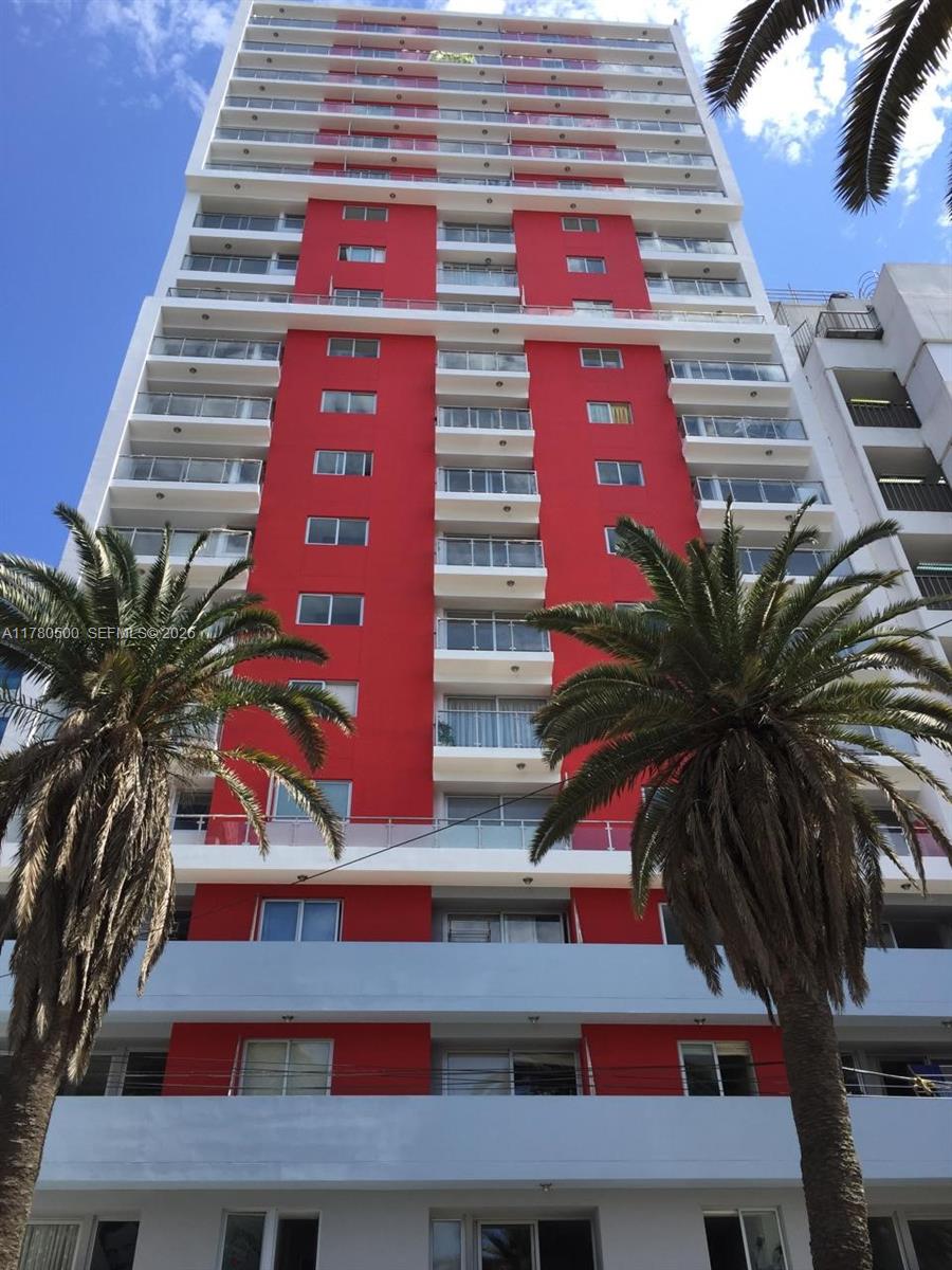 A low-angle view of a tall residential building featuring red vertical accents and palm trees — 175 Jiron Saco Oliveros PE # 1903, PE 0000, PE