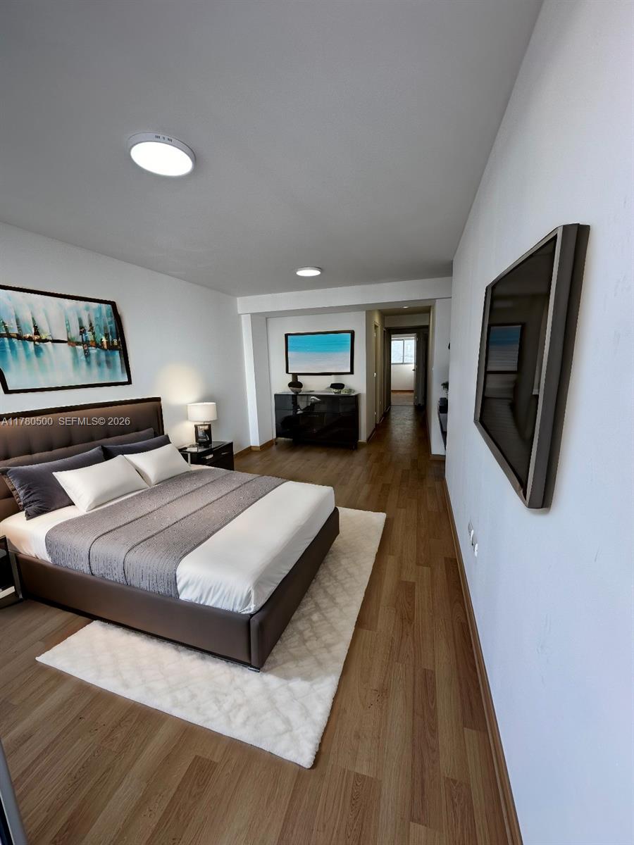 A bedroom features a bed with gray bedding, wood flooring, and wall-mounted artwork — 175 Jiron Saco Oliveros PE # 1903, PE 0000, PE