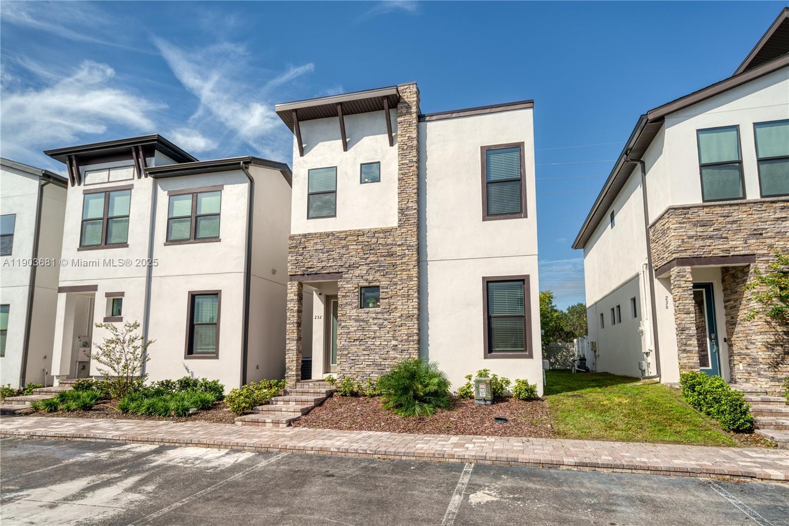 The exterior features a modern two-story townhouse with stone veneer accents and a paved walkway — 232 Villa Domani, Davenport FL 33896, DAVENPORT, FL
