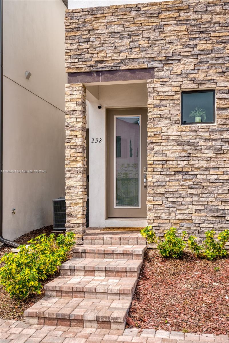 The exterior of a modern home features a stone facade, a glass-paneled door, and steps — 232 Villa Domani, Davenport FL 33896, DAVENPORT, FL