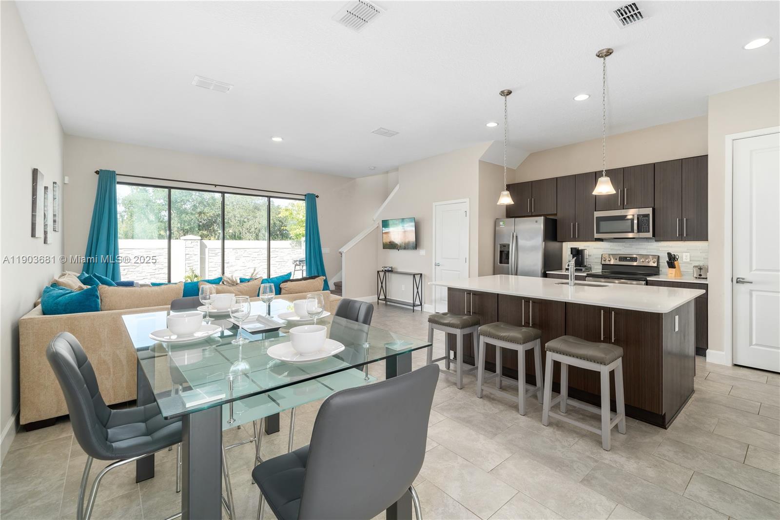 An open-concept kitchen and dining area features dark wood cabinetry, a quartz island, and tile flooring — 232 Villa Domani, Davenport FL 33896, DAVENPORT, FL