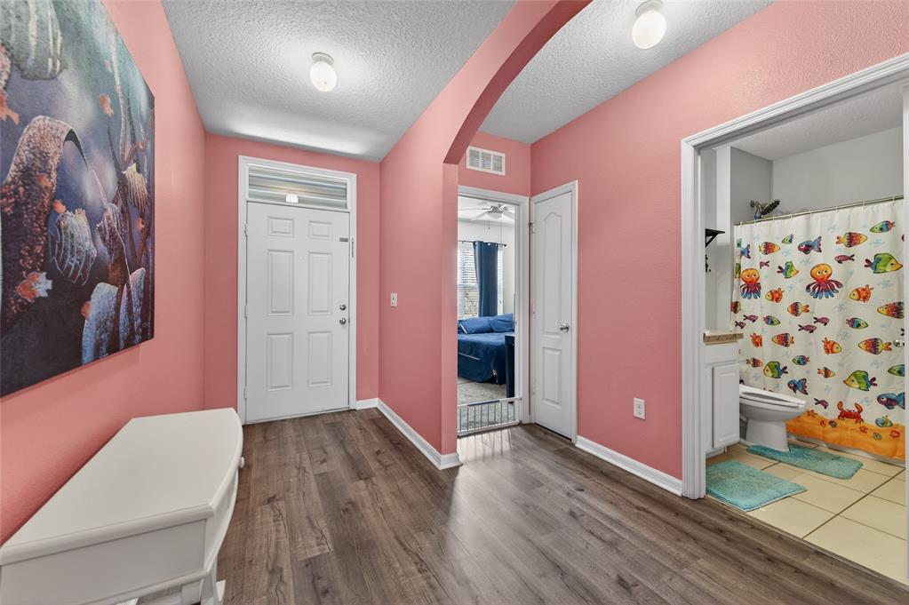 A pink-walled entryway features wood-look flooring, a white front door, and an adjacent bathroom — 113 FISHERMANS COVE DRIVE, EDGEWATER, FL