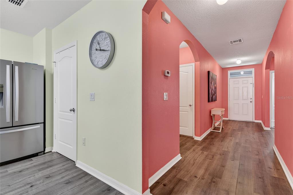 A view of a hallway with coral walls, wood-look flooring, and a white front door — 113 FISHERMANS COVE DRIVE, EDGEWATER, FL