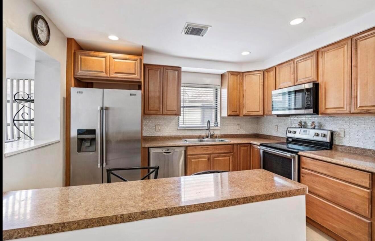 A kitchen features wood cabinets, granite countertops, stainless steel appliances, and a breakfast bar — 6089 Glentree Lane, FL 33463, FL