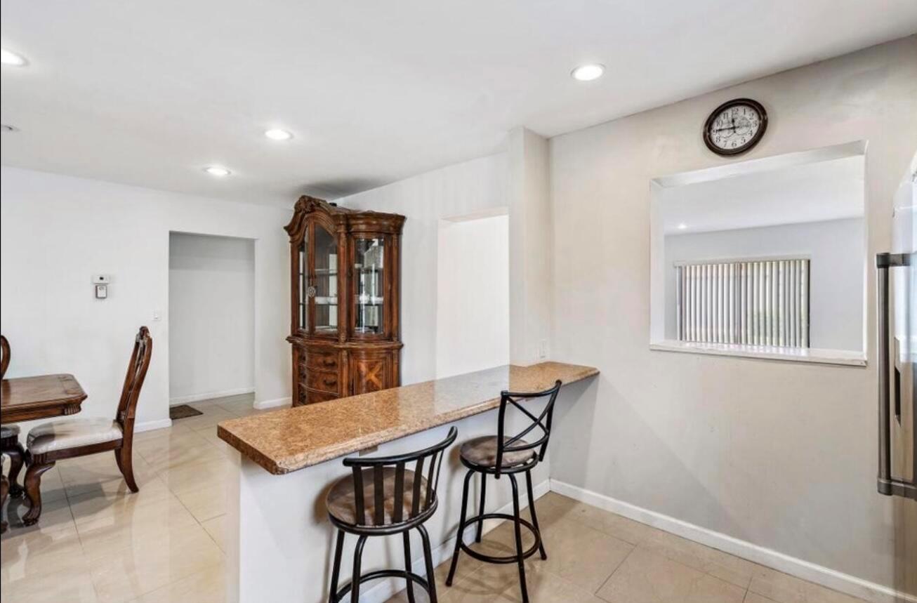 A kitchen breakfast bar with granite countertops, two stools, and a wooden hutch nearby — 6089 Glentree Lane, FL 33463, FL