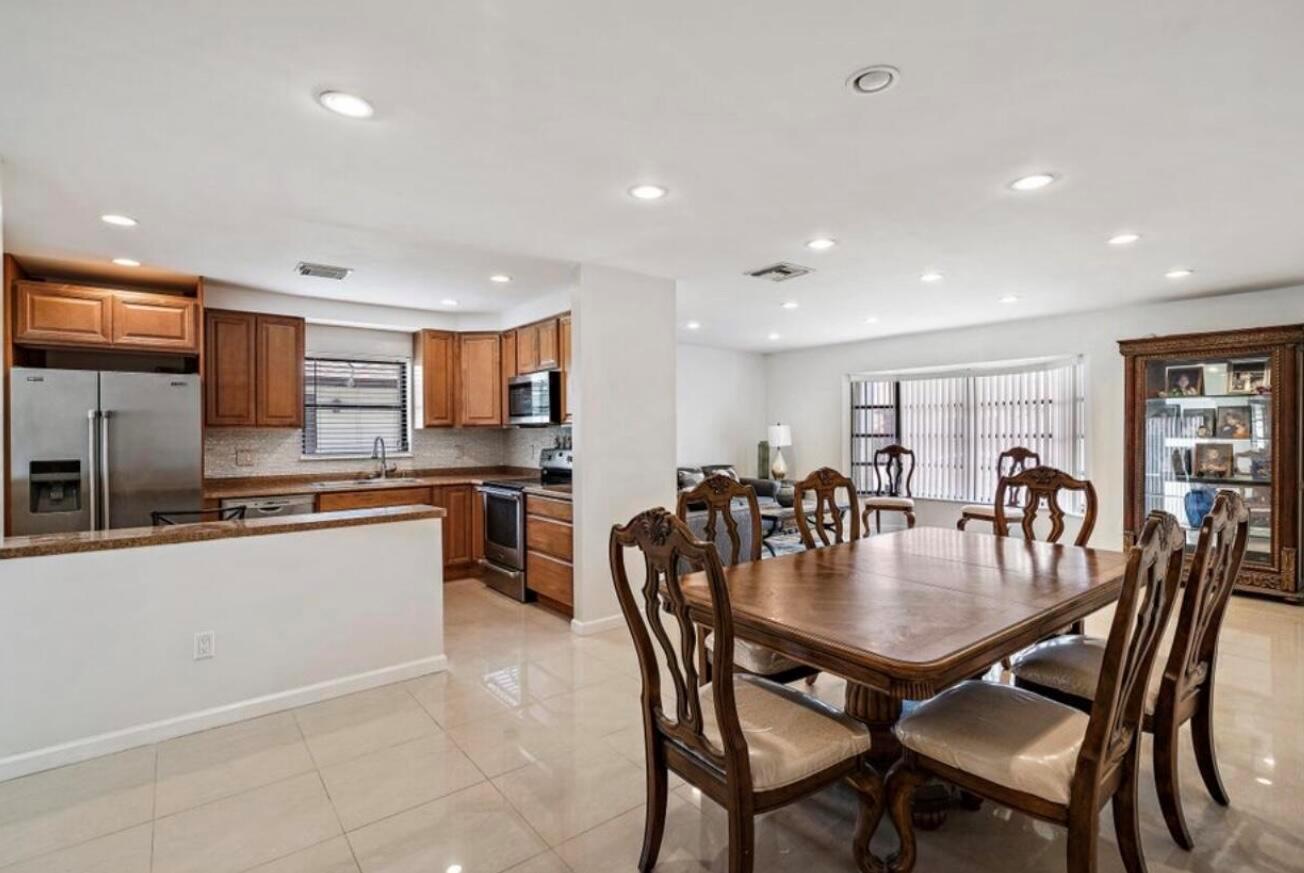 A dining area with a wooden table and chairs adjacent to an open-concept kitchen — 6089 Glentree Lane, FL 33463, FL
