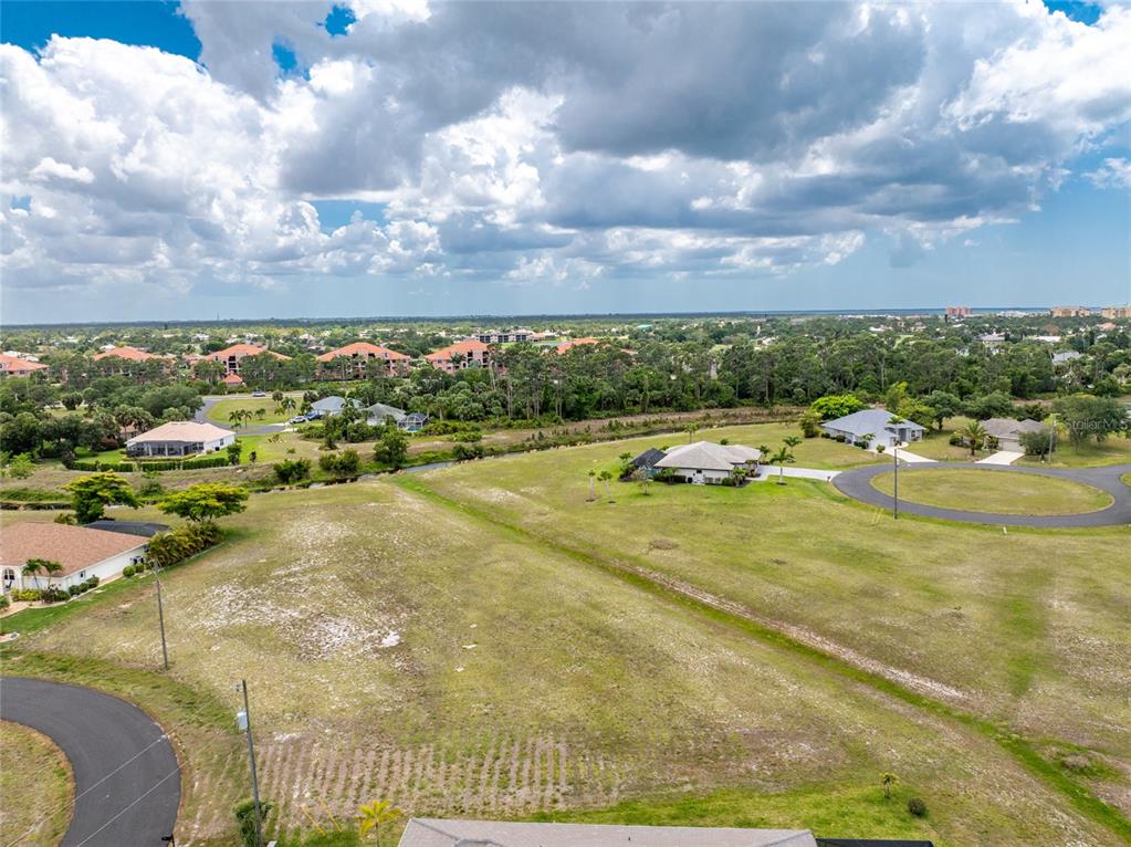 An aerial view shows a vacant grassy lot surrounded by residential homes and trees — 17508 & 17514 VELLUM CIRCLE, PUNTA GORDA, FL