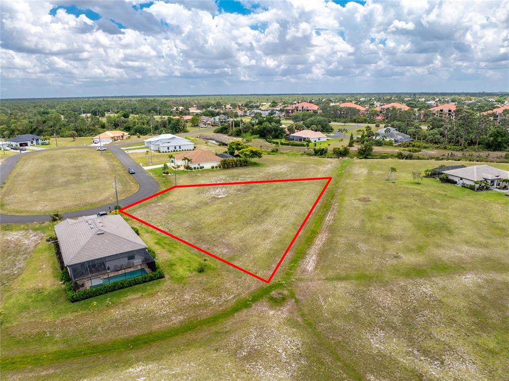 An aerial view shows a vacant, triangular-shaped residential lot outlined in red next to a house — 17508 & 17514 VELLUM CIRCLE, PUNTA GORDA, FL