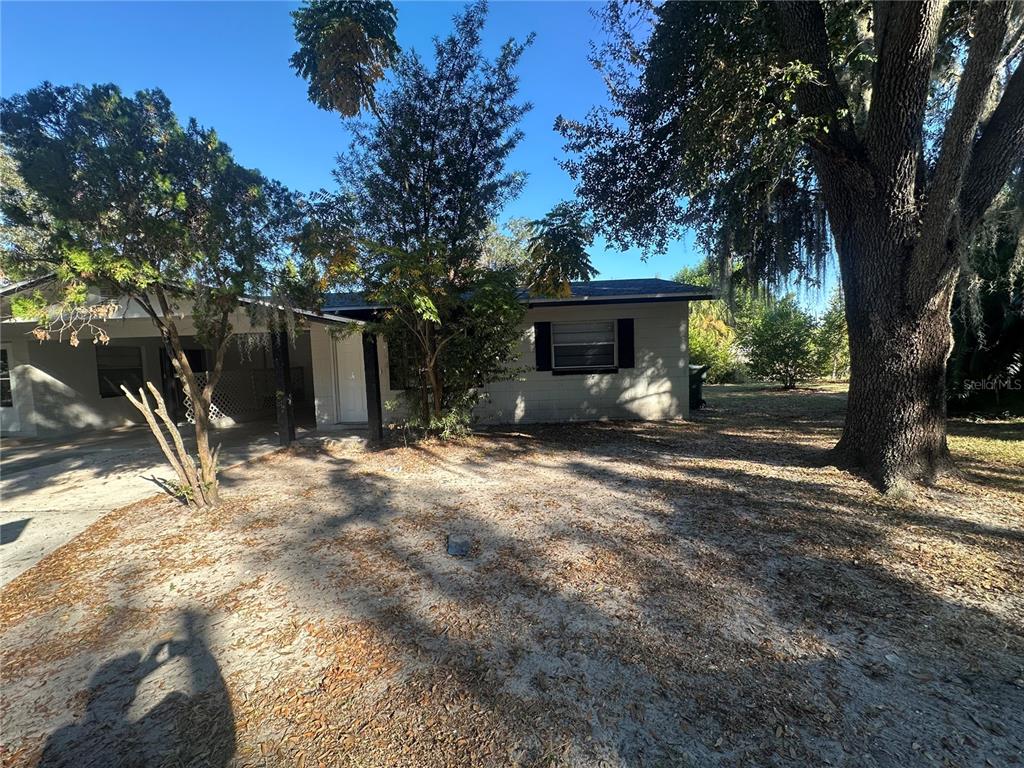 A single-story house with a carport and a large tree in the front yard — 1615 N NEW YORK AVENUE, LAKELAND, FL