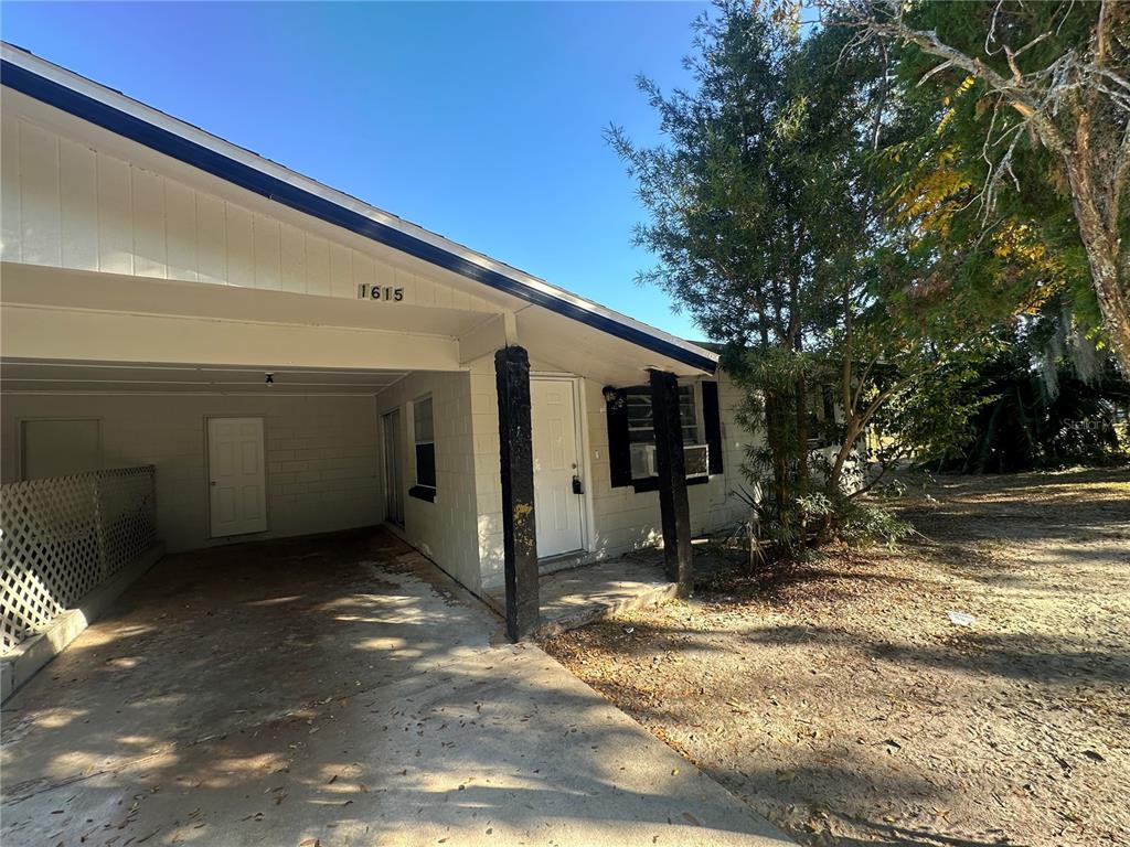 A single-story house with a carport, white exterior walls, and a dark-trimmed roof — 1615 N NEW YORK AVENUE, LAKELAND, FL