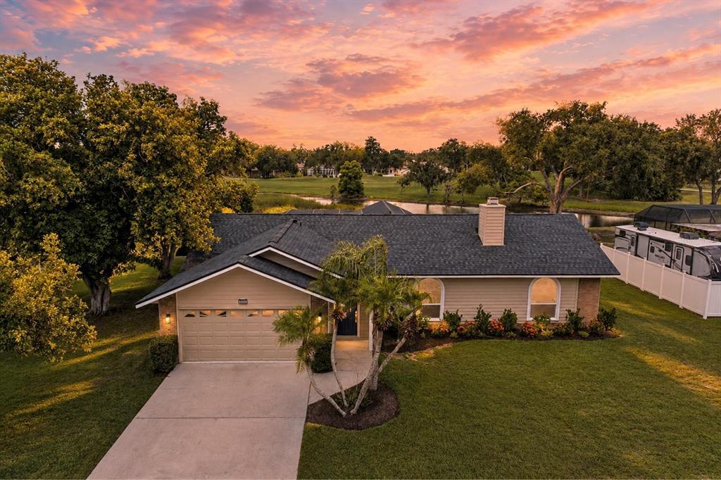 An aerial view of a single-story house with a garage, driveway, and backyard pond — 6221 99TH STREET E, BRADENTON, FL