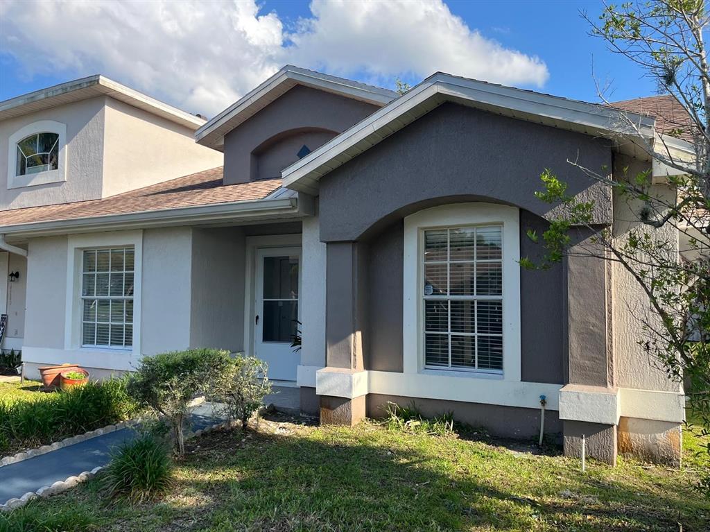 A single-story house with a gray stucco exterior, white trim, and a front entrance — 14776 LAGUNA BEACH CIRCLE, ORLANDO, FL