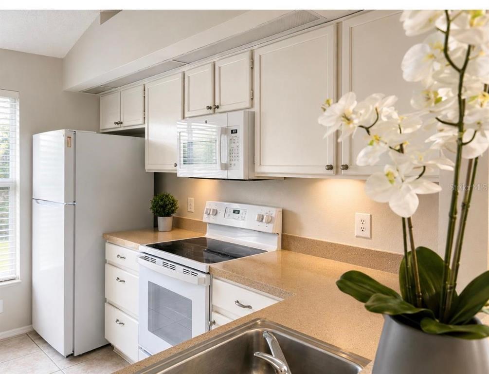 A kitchen with white cabinets, white appliances, and tan countertops — 14776 LAGUNA BEACH CIRCLE, ORLANDO, FL