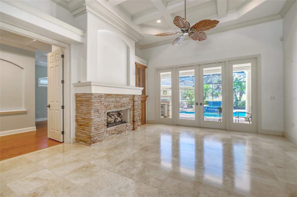 A living room features a stone fireplace, tile flooring, a coffered ceiling, and glass doors — 2983 WENTWORTH WAY, TARPON SPRINGS, FL