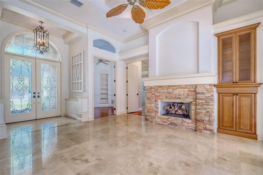 A spacious foyer features a stone fireplace, tile flooring, and a decorative ceiling fan — 2983 WENTWORTH WAY, TARPON SPRINGS, FL