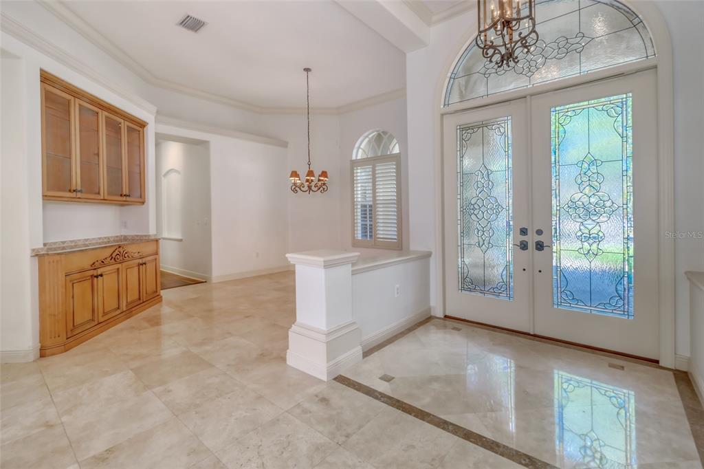 An entryway features marble floors, a built-in wooden hutch, and double doors with stained glass — 2983 WENTWORTH WAY, TARPON SPRINGS, FL