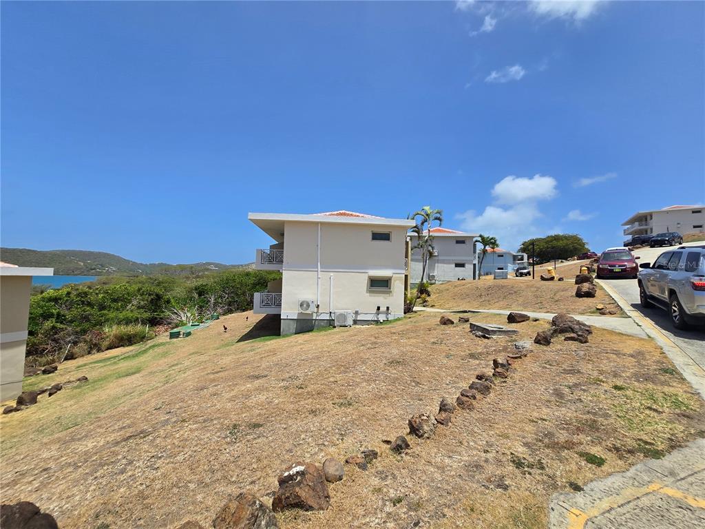 A multi-story residential building sits on a grassy hillside near a paved road — Punta Canero,BO. Frailes COSTA BONITA UNIT 1702, CULEBRA, PR