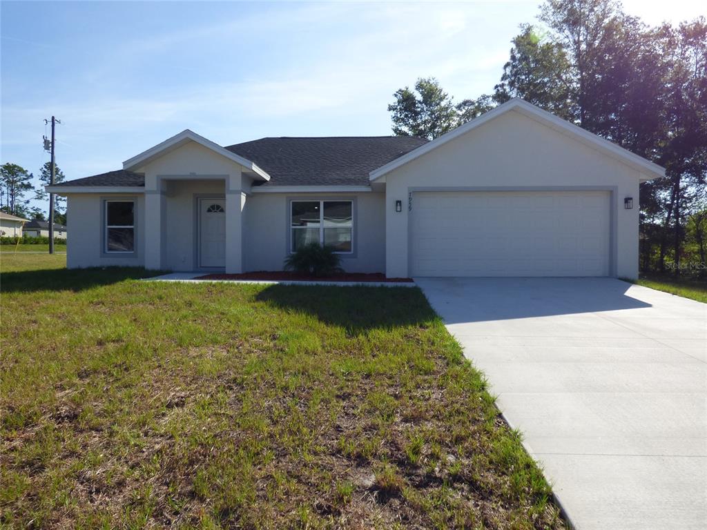 A single-story house with a white stucco exterior, a two-car garage, and a concrete driveway — 7959 N INDEPENDENCE WAY, CITRUS SPRINGS, FL