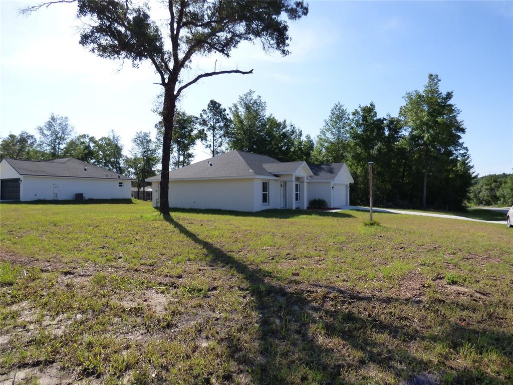 A single-story house with a white exterior and a garage sits on a grassy lot — 7959 N INDEPENDENCE WAY, CITRUS SPRINGS, FL