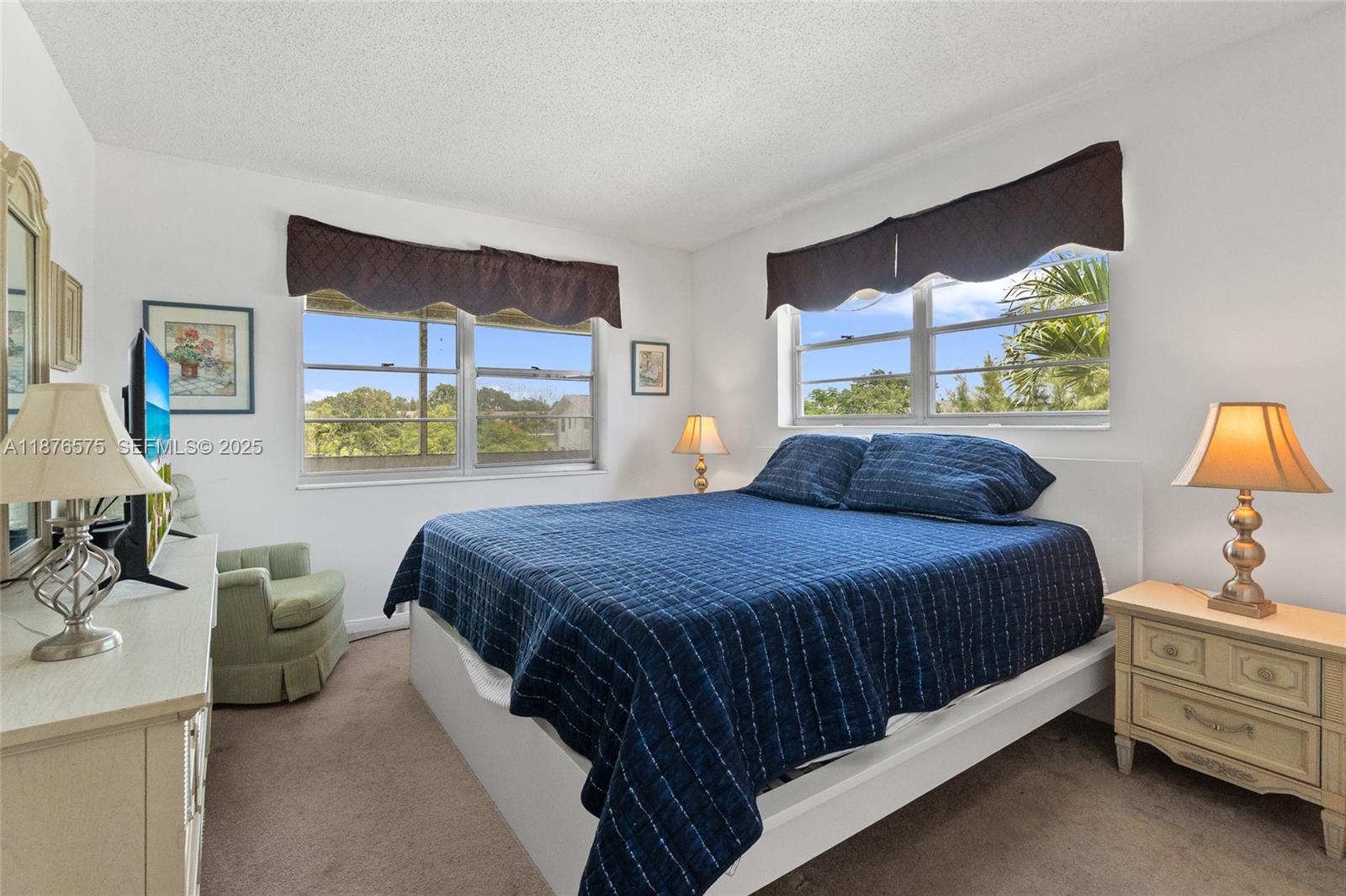 A bedroom features a blue quilt on a white bed frame, two windows, and lamps — 431 Markham T # 431, Deerfield Beach FL 33442, DEERFIELD BEACH, FL
