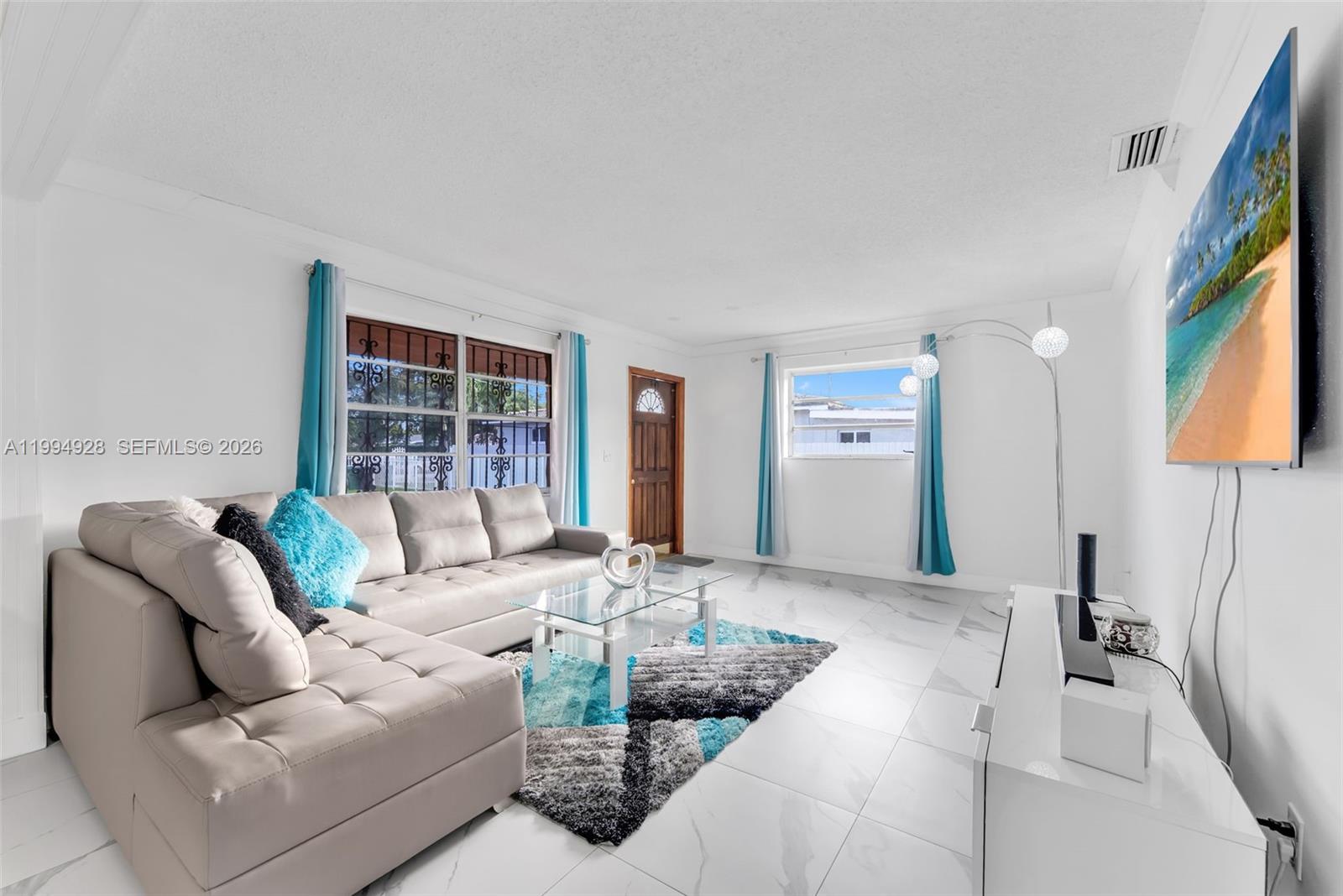 A living room features a light gray sectional sofa, a glass coffee table, and tile flooring — 8820 SW 27th St, Miami FL 33165, MIAMI, FL
