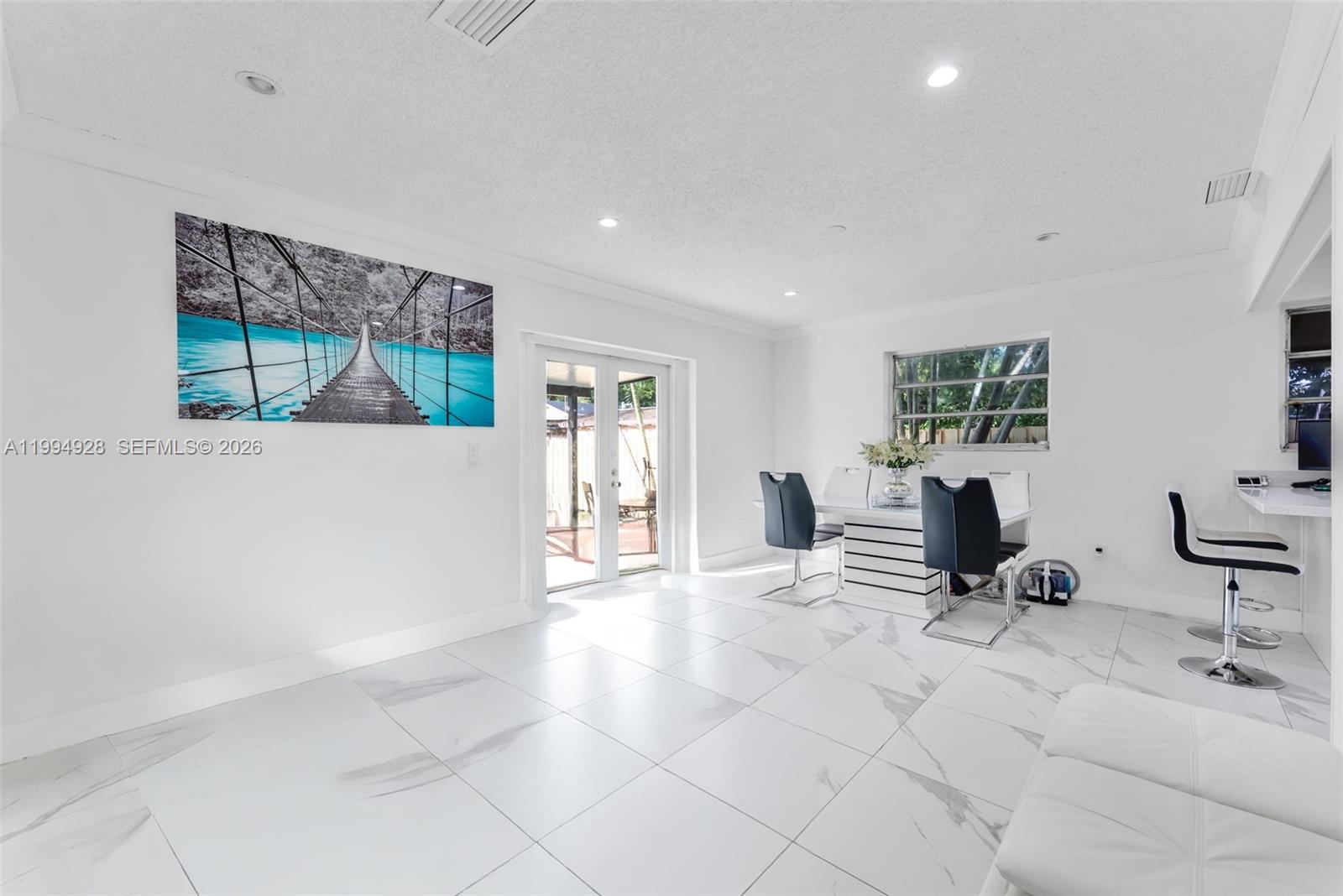 A bright dining area features white marble-look tile floors, a modern table, and wall art — 8820 SW 27th St, Miami FL 33165, MIAMI, FL