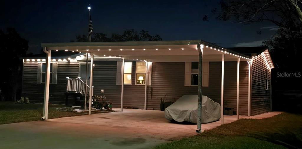 A single-story house with a covered carport and string lights at night — 210 PHILADELPHIA COURT UNIT 17, PALM HARBOR, FL