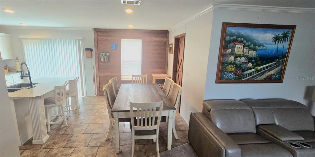 An open-concept dining area and kitchen feature wood-paneled walls, tile flooring, and a leather sofa — 210 PHILADELPHIA COURT UNIT 17, PALM HARBOR, FL