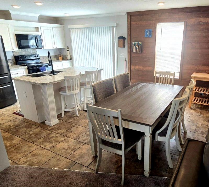 A kitchen with a center island and a dining area featuring a wood-paneled accent wall — 210 PHILADELPHIA COURT UNIT 17, PALM HARBOR, FL