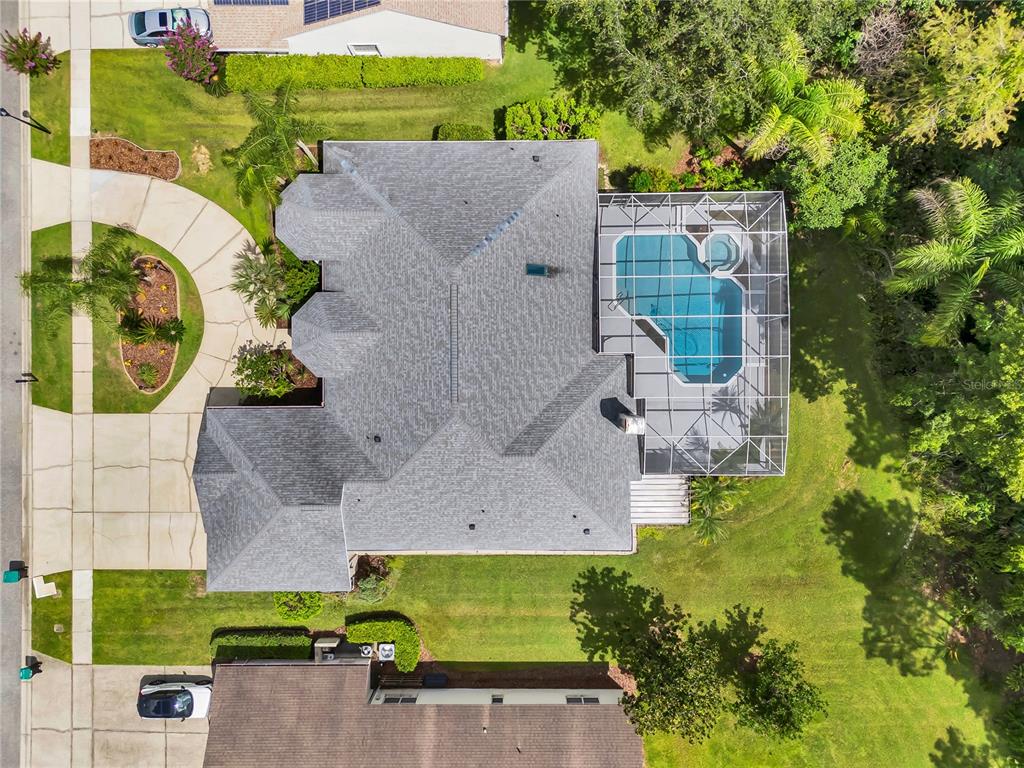 An aerial view shows a house with a gray roof, a screened pool, and landscaping — 4749 SUDBURY DRIVE, ORLANDO, FL
