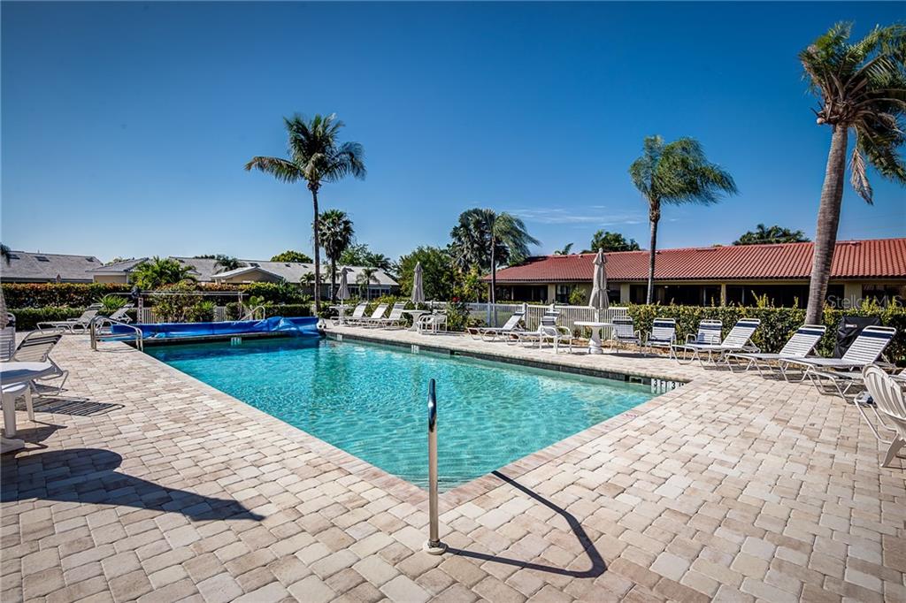 A rectangular swimming pool surrounded by a paved deck with lounge chairs and palm trees — 2601 W MARION AVENUE UNIT 47A, PUNTA GORDA, FL