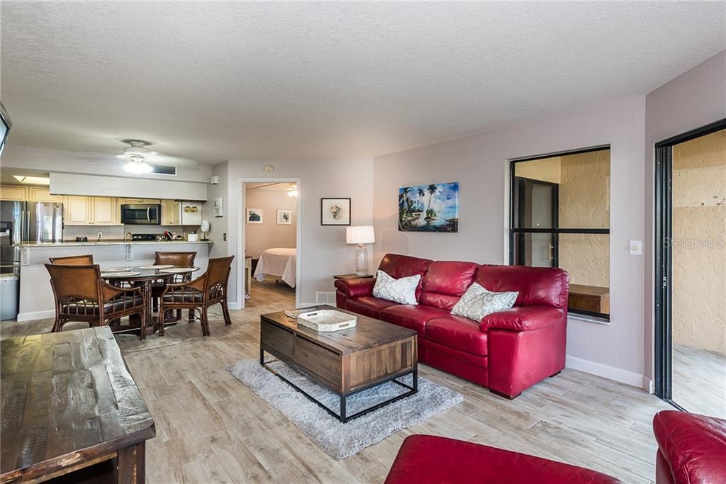 A living room with a red leather sofa, wooden coffee table, and adjacent dining area — 2601 W MARION AVENUE UNIT 47A, PUNTA GORDA, FL