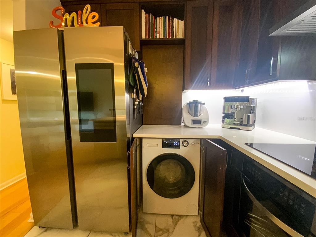 A kitchen features dark wood cabinets, stainless steel appliances, a white countertop, and a washing machine — 3134 LAKE PINE WAY UNIT C2, TARPON SPRINGS, FL