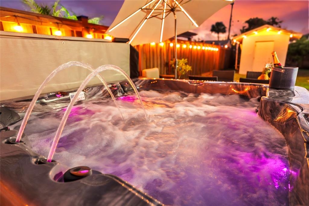 A hot tub with illuminated water jets sits on a patio at dusk — 363 HARBOR DR, CAPE CANAVERAL, FL