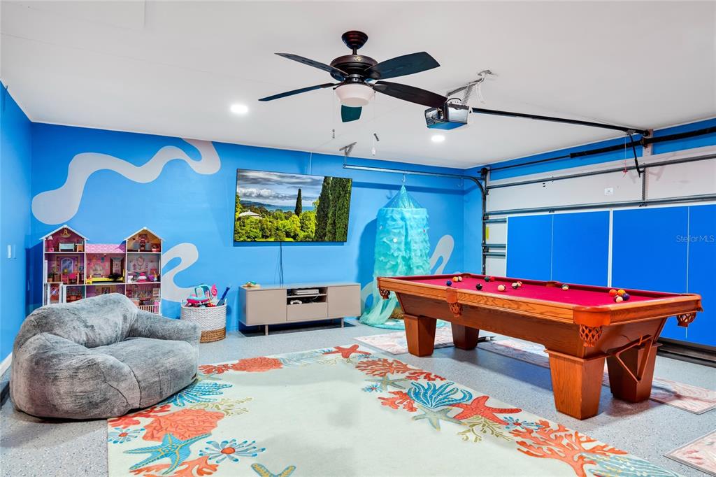 A blue-walled garage converted into a playroom with a pool table and a television — 363 HARBOR DR, CAPE CANAVERAL, FL