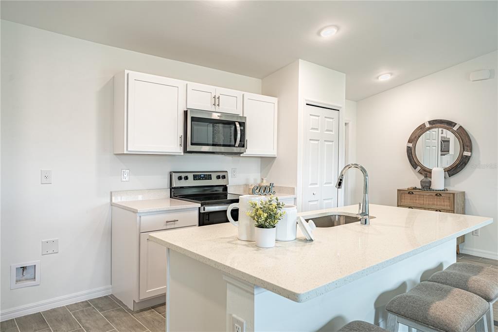 A kitchen with white cabinets, a quartz island, stainless steel appliances, and gray tile flooring — 364 LINDON STREET, PORT CHARLOTTE, FL