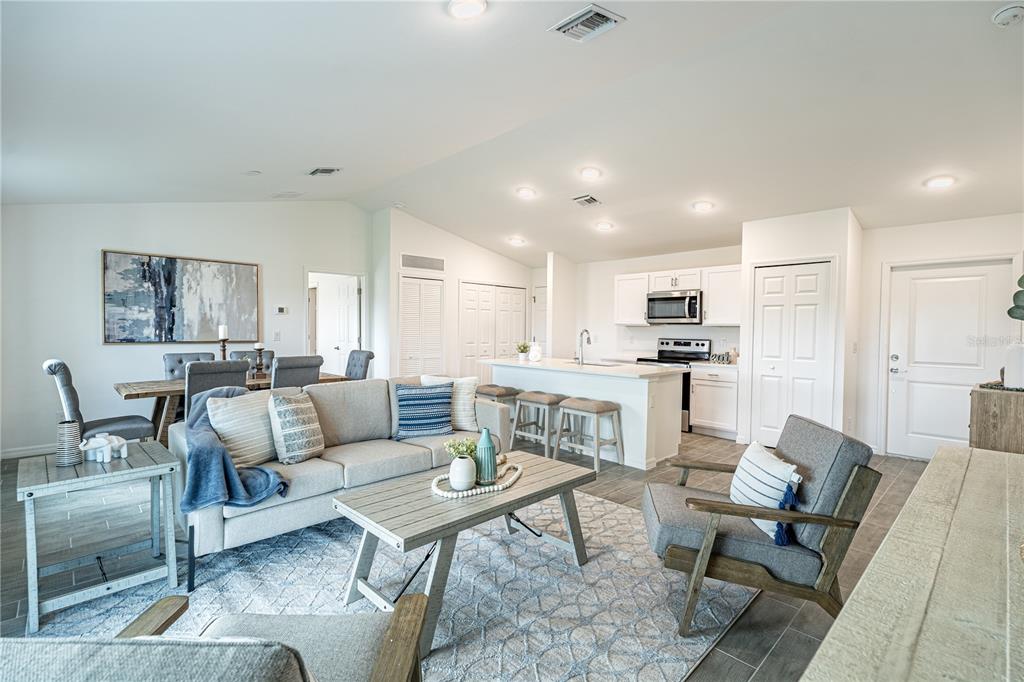 An open-concept living room and kitchen featuring light-colored furniture, a kitchen island, and tile flooring — 364 LINDON STREET, PORT CHARLOTTE, FL