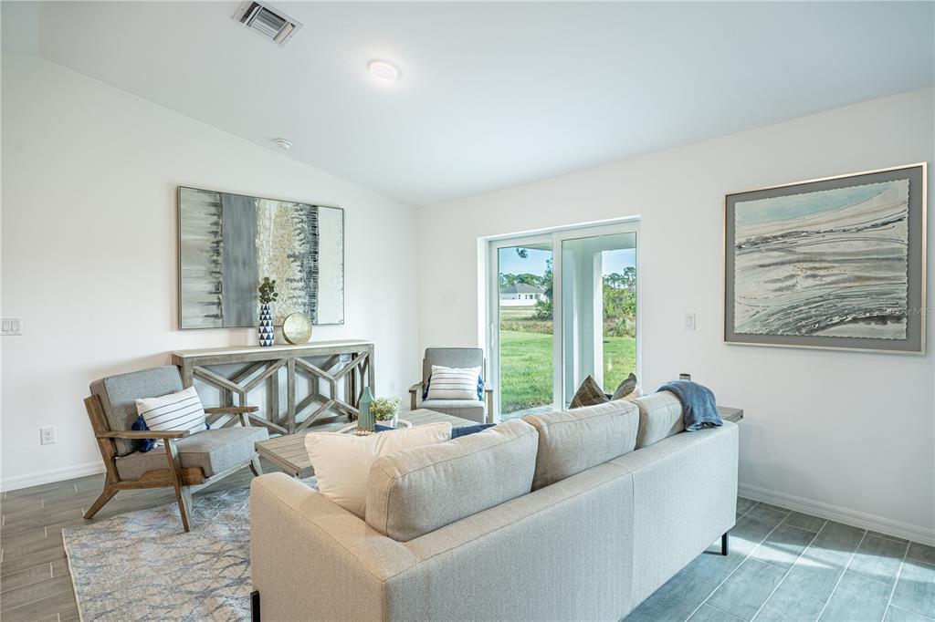 A living room features a grey sofa, two armchairs, a console table, and sliding glass doors — 364 LINDON STREET, PORT CHARLOTTE, FL