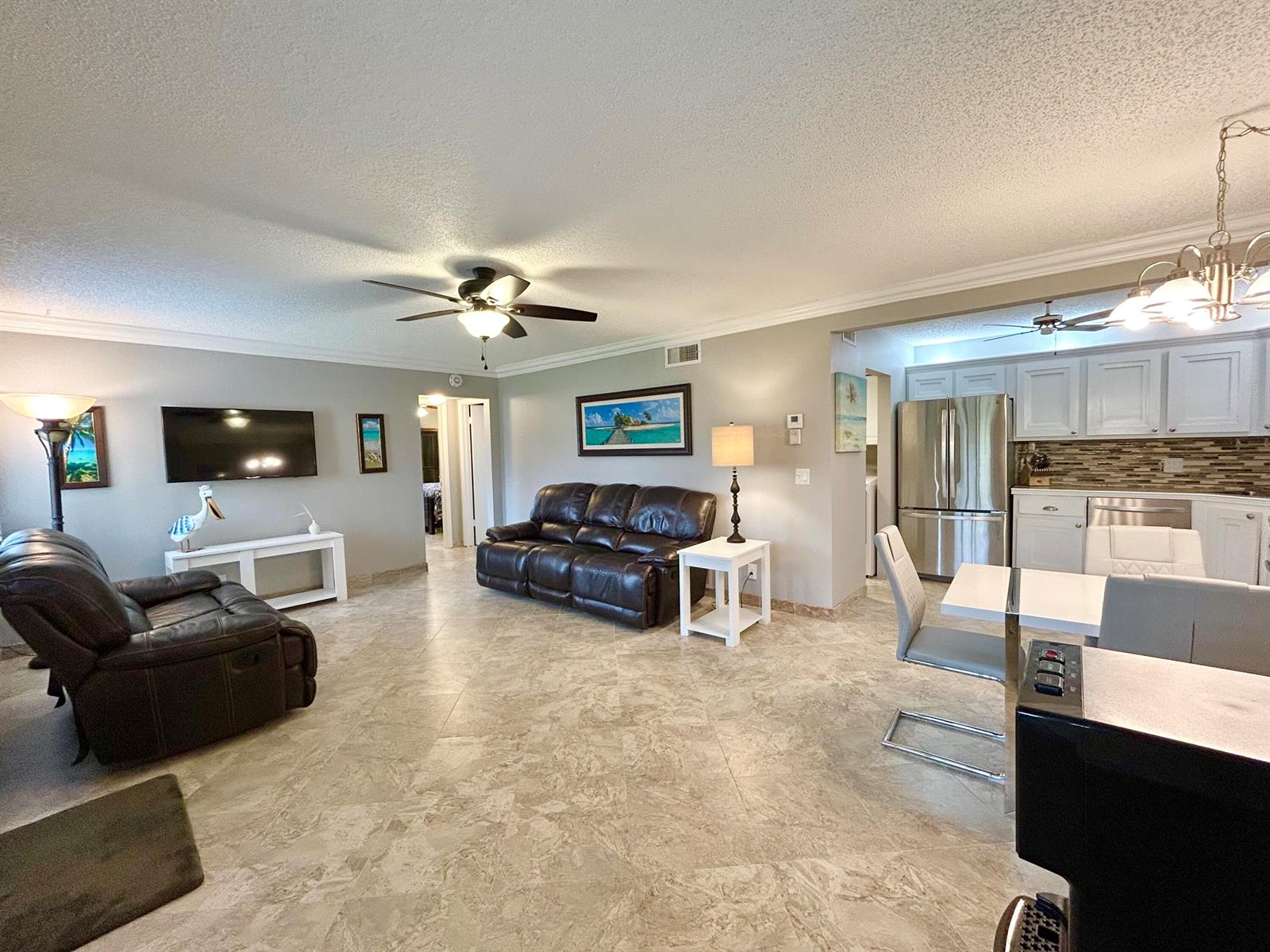 An open-concept living room and kitchen feature tile flooring, leather furniture, and stainless appliances — 223 Pine Hov Circle # 2, FL 33463, FL