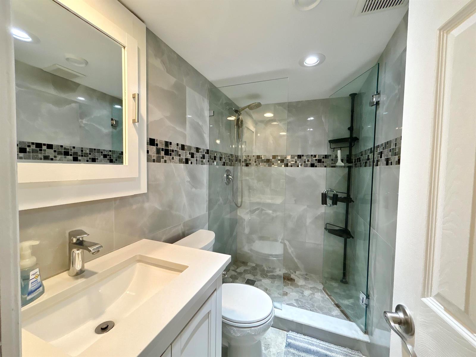 A bathroom features a white vanity, a toilet, and a glass-enclosed shower with tiled walls — 223 Pine Hov Circle # 2, FL 33463, FL