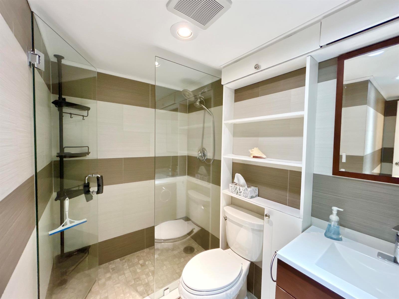 A modern bathroom features a glass-enclosed shower, a toilet, and a white vanity with shelving — 223 Pine Hov Circle # 2, FL 33463, FL