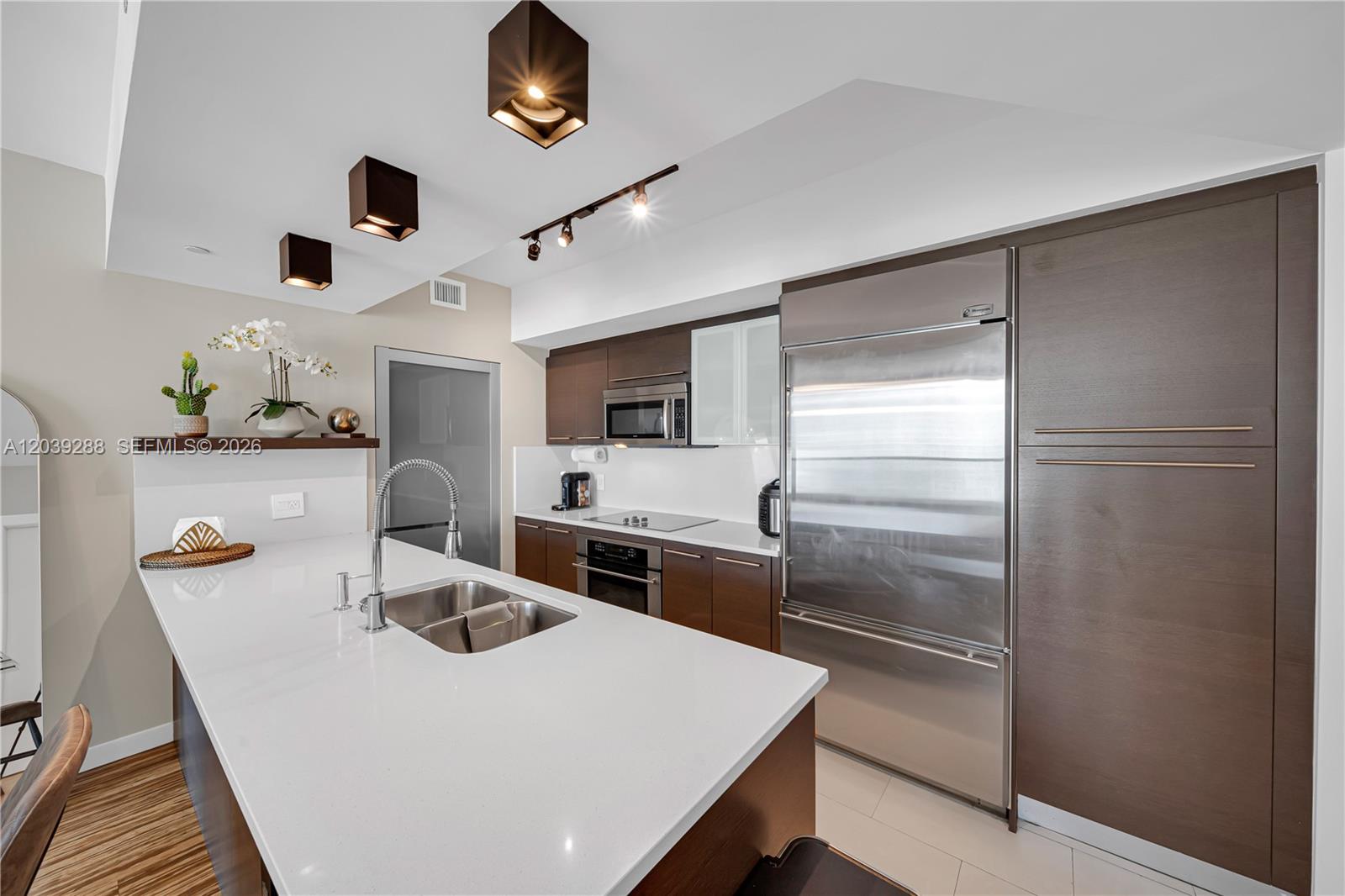 A modern kitchen features a white island, stainless steel appliances, and dark wood cabinetry — MIAMI, FL