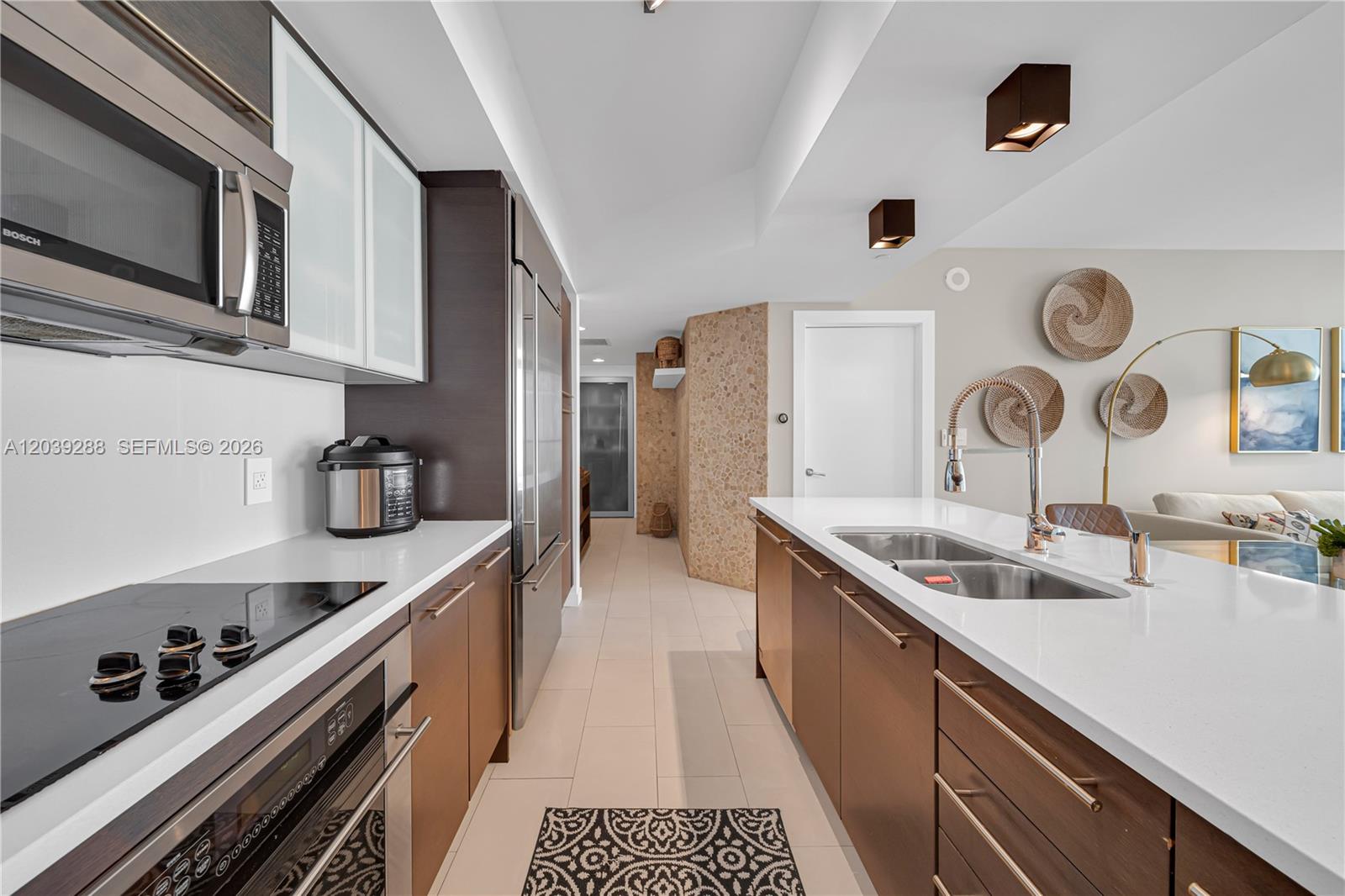 A modern kitchen features dark wood cabinetry, white countertops, stainless steel appliances, and tile flooring — MIAMI, FL