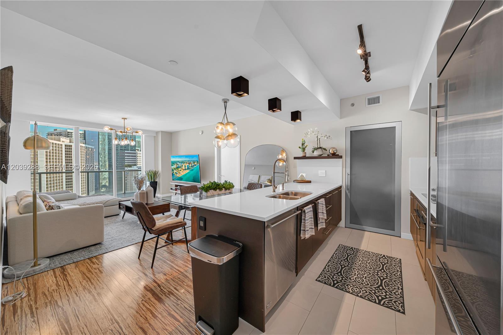 A modern open-concept kitchen and living area features a kitchen island, stainless appliances, and balcony — MIAMI, FL